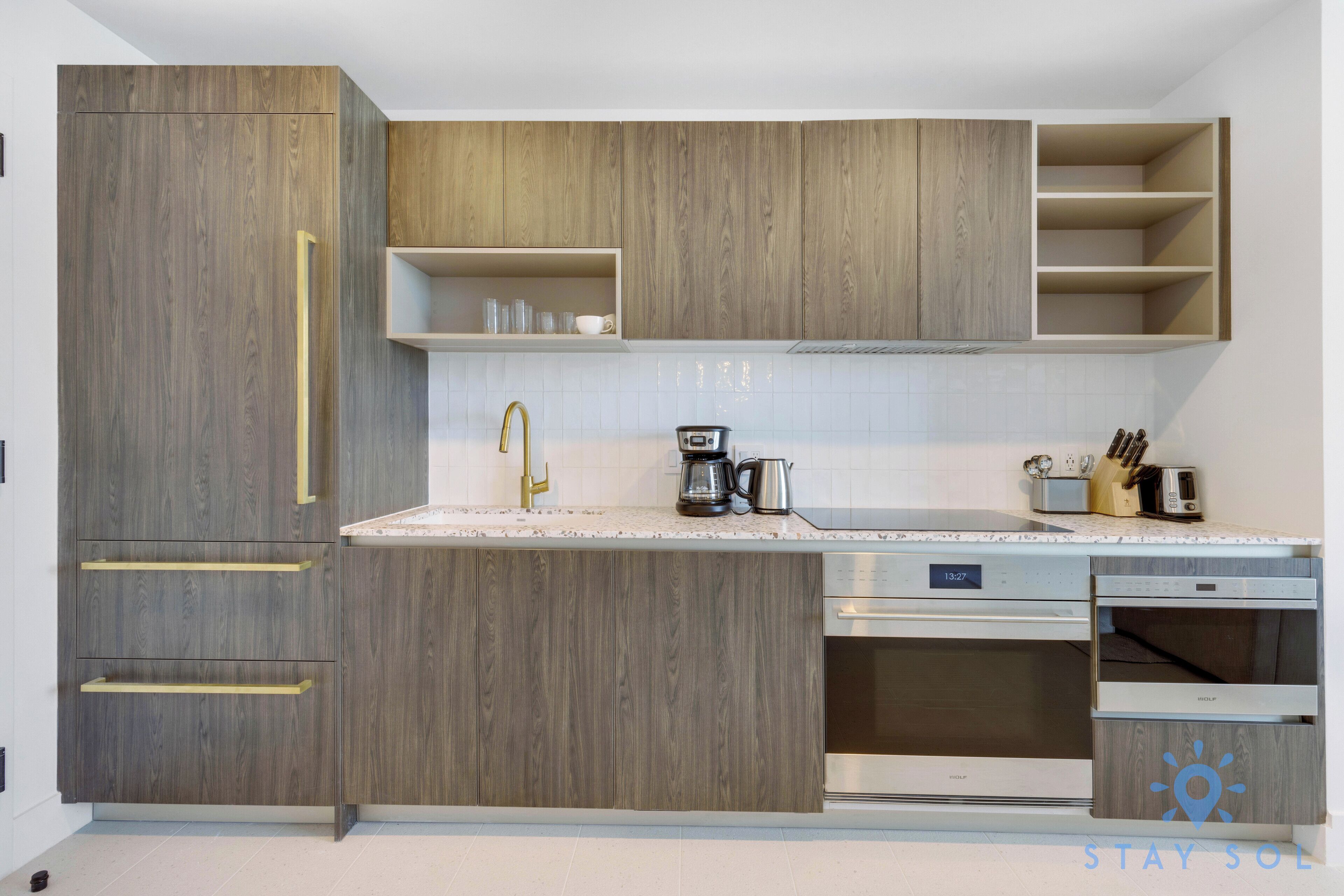 A modern kitchen with wooden cabinets, a stainless steel dishwasher, and a coffee maker.