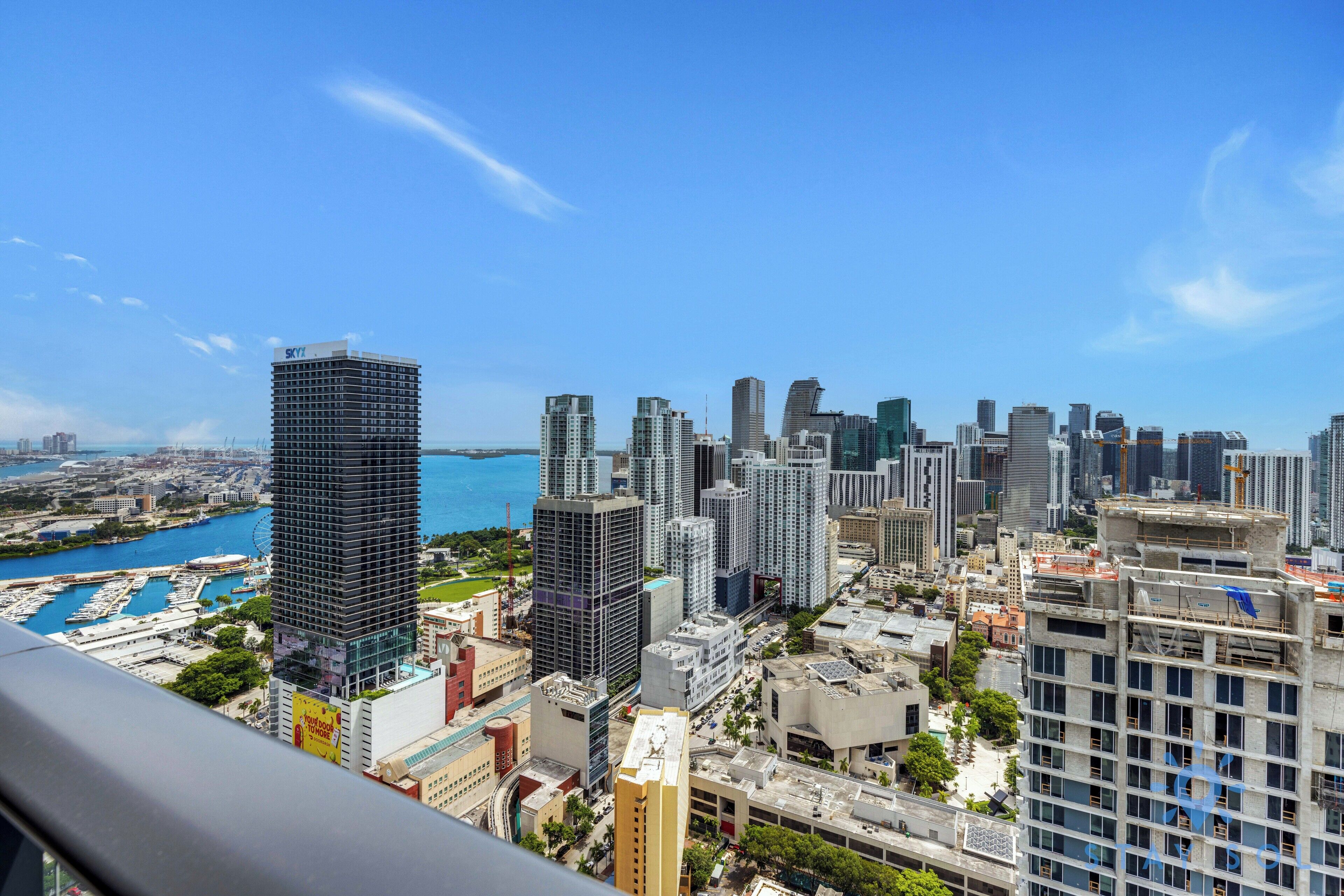 Un paysage urbain avec de hauts immeubles, une marina et un ciel bleu dégagé.