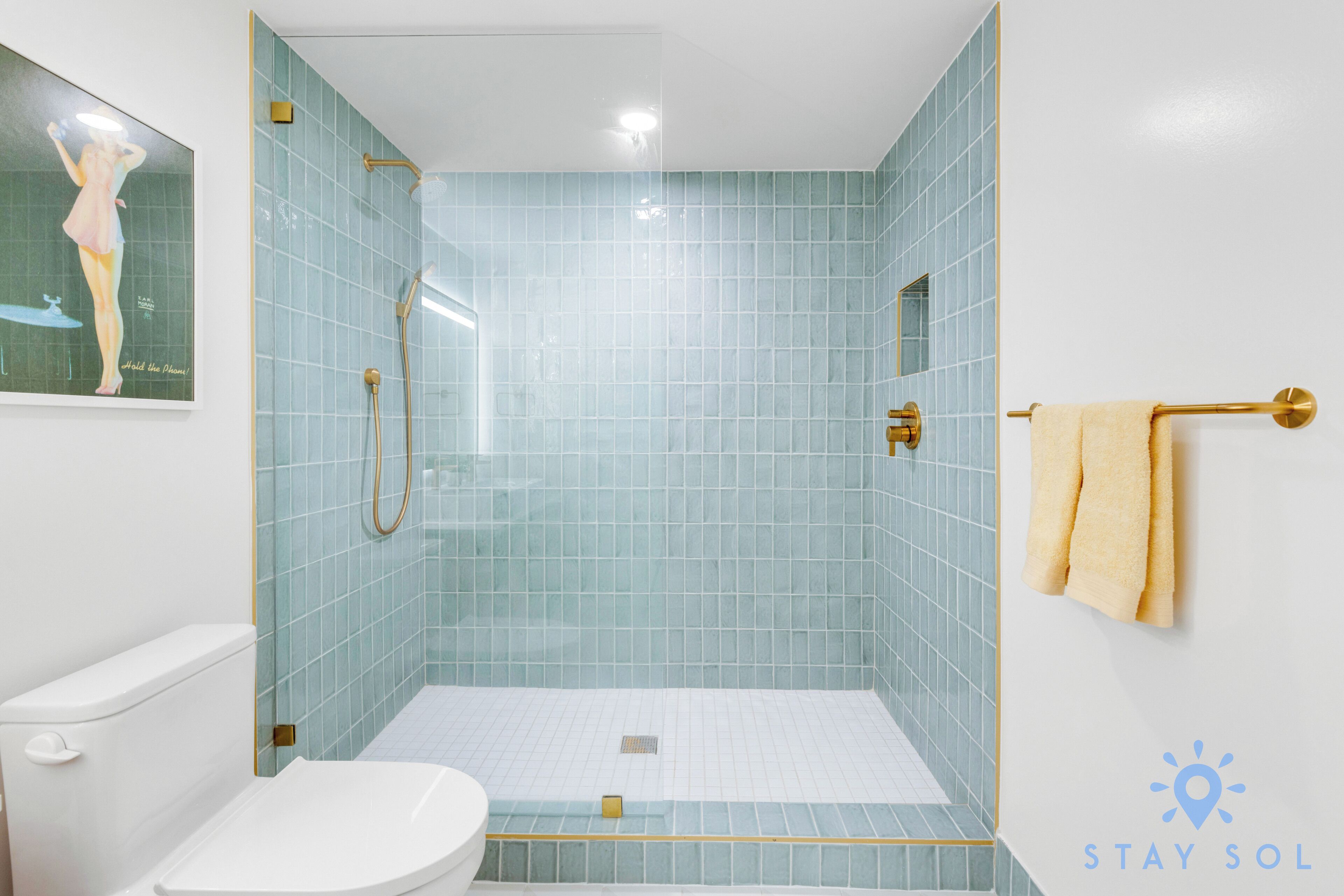 A bathroom with a glass-enclosed shower, a toilet, and a towel rack.