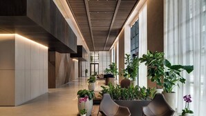 A modern lobby with a high ceiling, large windows, and a variety of plants. - Stay Sol Downtown (Miami)