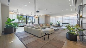 A spacious living area with a large sofa, coffee table, and potted plants. - Stay Sol Downtown (Miami)