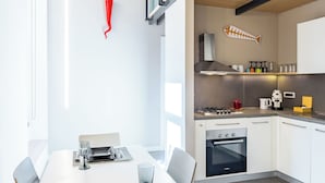 Eine moderne Küche mit Essbereich, mit einem weißen Tisch für zwei Personen, einem Gasherd und einem eingebauten Backofen.