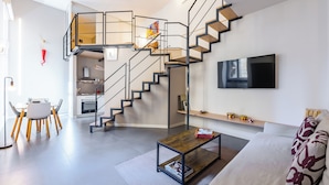 Ein modernes Wohnzimmer mit Treppe, Essbereich und Küche.