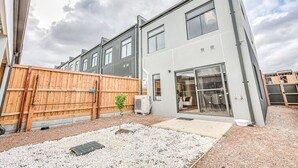 A modern two-story house with a fenced backyard, a small garden, and a visible air conditioning unit. - StayAU Fresh Modern 5BR Retreat Netflix in Berwick (Berwick)