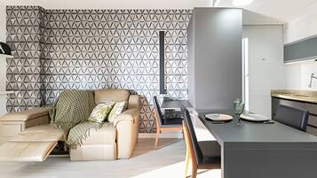 A modern living room with a sofa, a dining table, and a kitchen area.