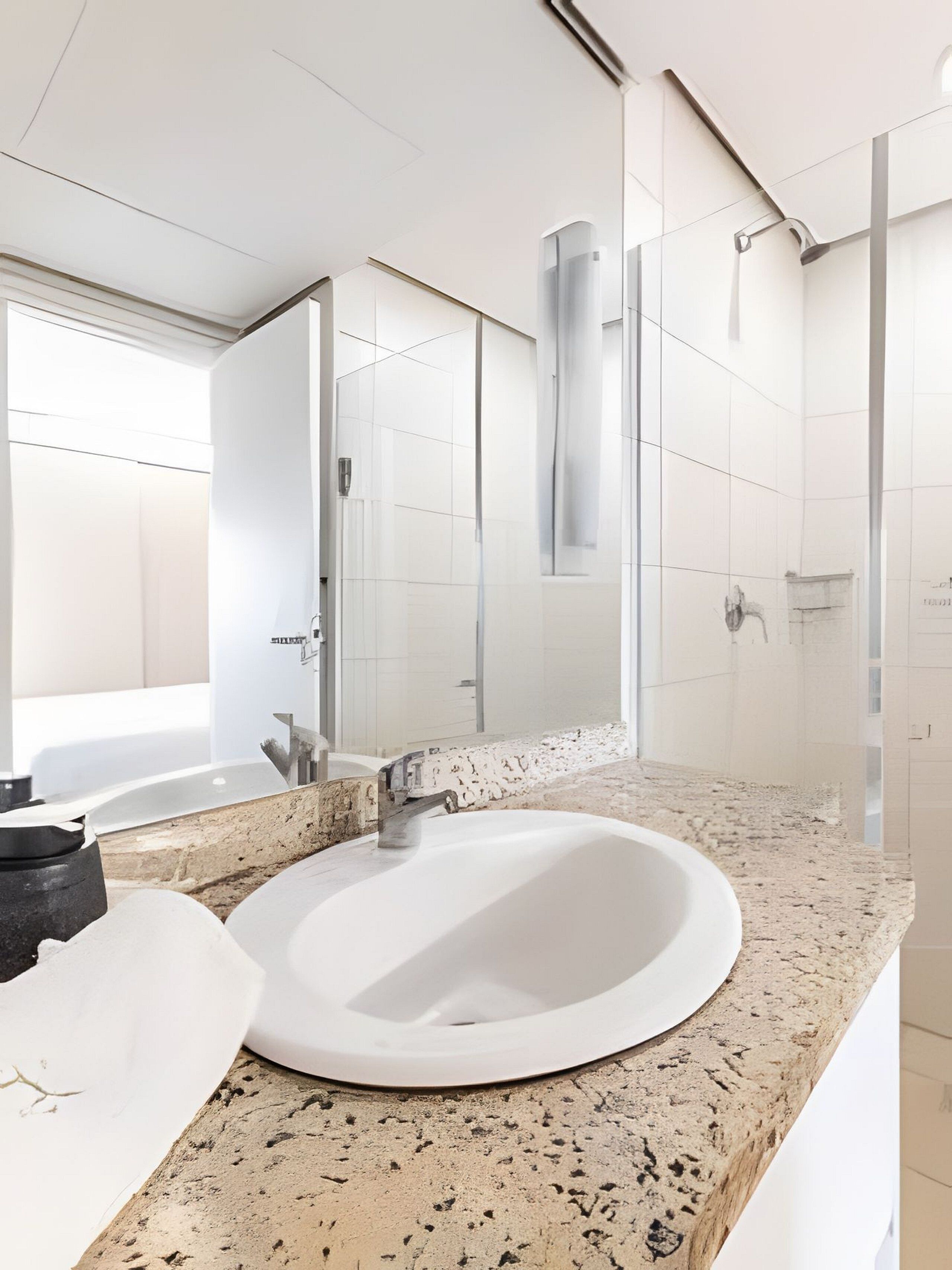 A modern bathroom with a large sink, a mirror, and a shower area.