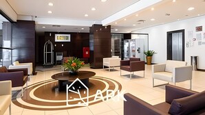 A modern lobby with a central coffee table, seating area, and a reception desk.