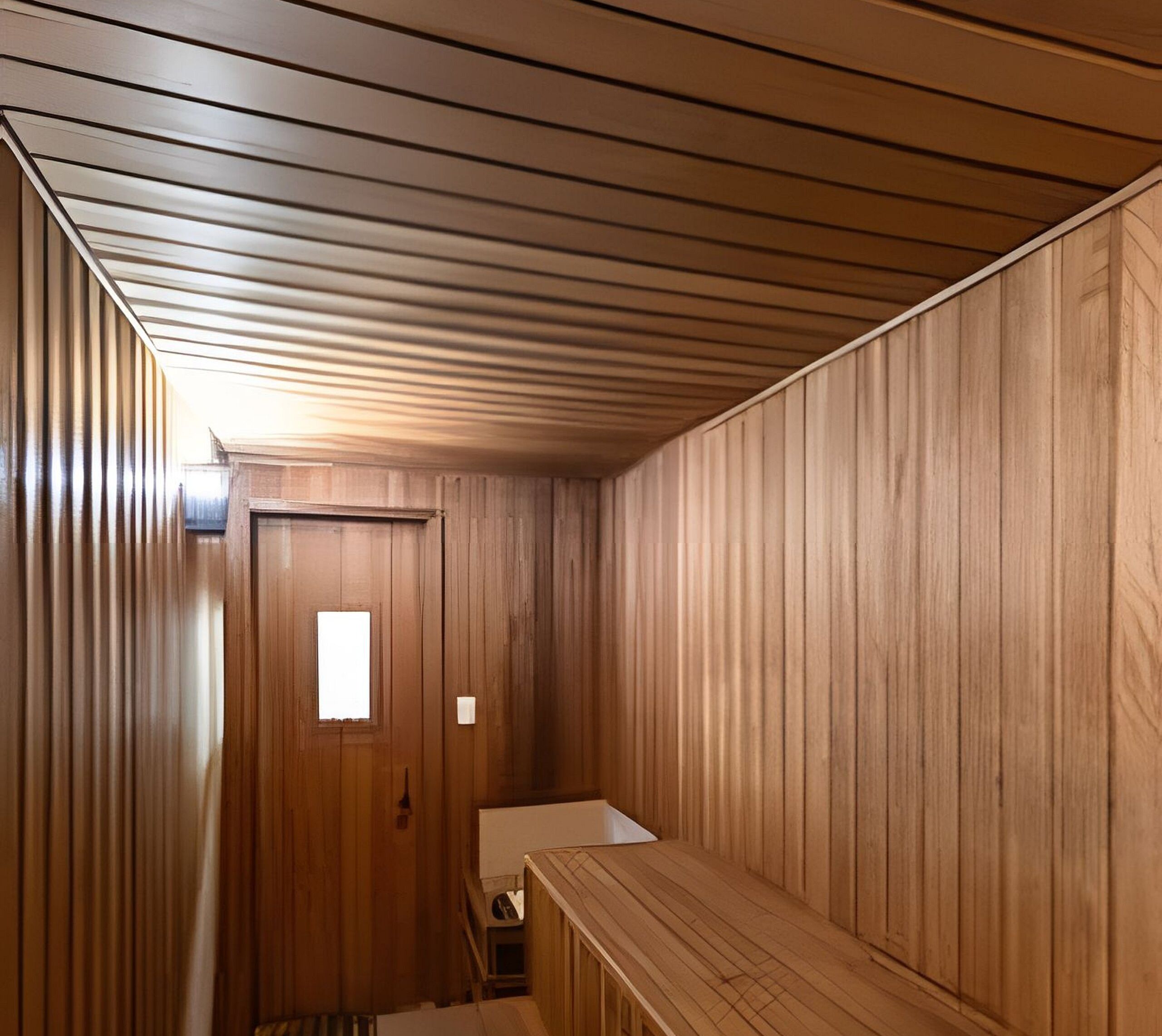 A room with wooden walls and a sloped ceiling. There is a door with a small window and a light switch on the wall.