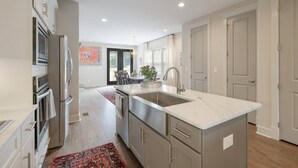 A modern kitchen with stainless steel appliances, a marble island, and a view to the dining area.