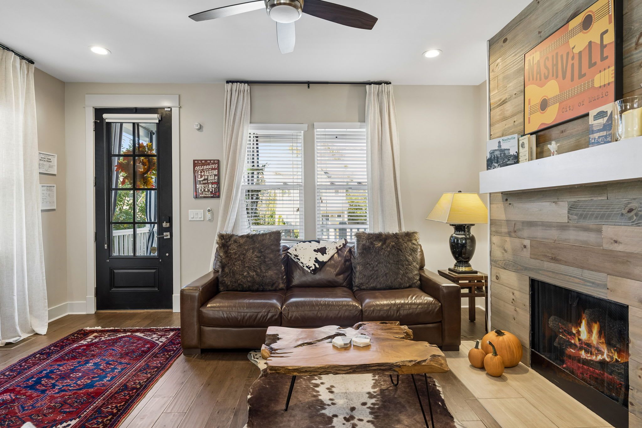 A living room with a leather sofa, a coffee table, a fireplace, and a window with blinds.