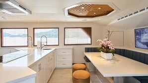 Una cocina moderna con una isla central, una zona de comedor con banco y ventanas grandes con persianas.