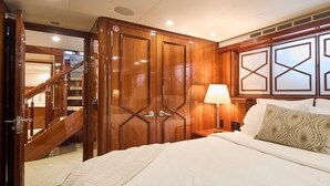 Un dormitorio con una cama grande, un armario de madera y una escalera que lleva a otra habitación.
