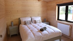 A wooden-paneled bedroom with a bed, nightstands, and a window.