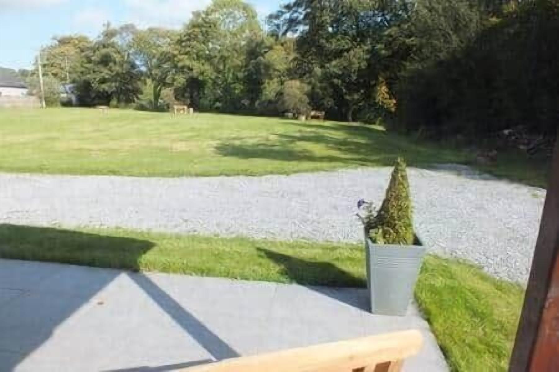 A view from a balcony with a grassy lawn, a gravel path, and a small tree.