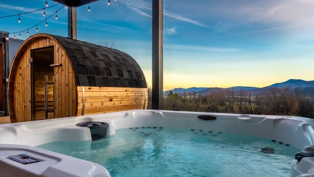 A hot tub with a wooden structure in the background and a mountainous view. - Modern A-Frame w/ Hot Tub, Sauna & Stunning Views (Stanley)