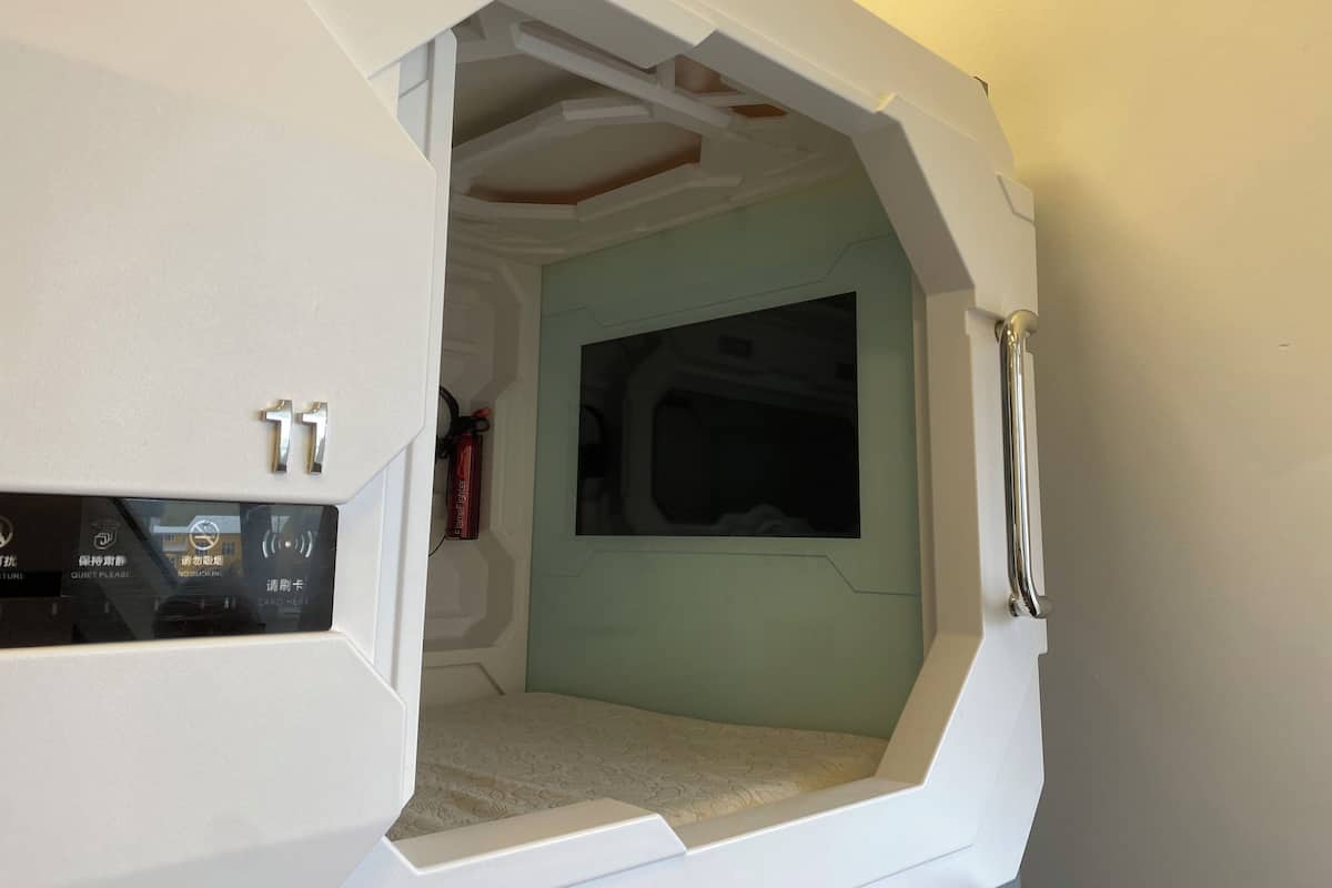 A room with a bed, a window, and a control panel with buttons and a display.
