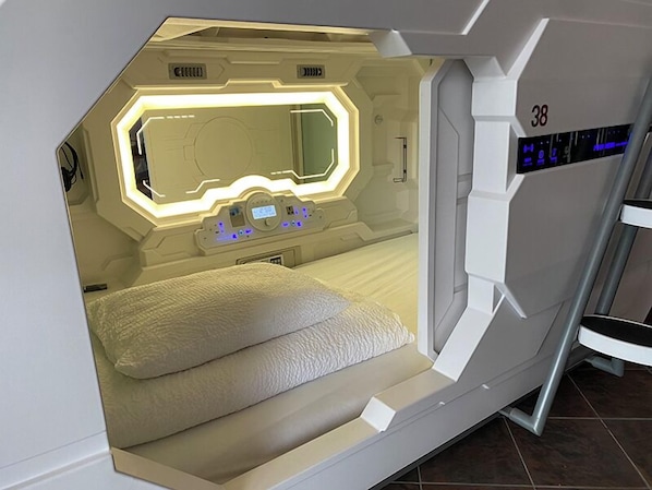 Una habitación futurista con una cama, un panel de control y una pantalla digital.