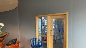 A modern interior with a round table, orange chairs, and a unique blue hand-shaped chair. - Blue Hostel Bláu Fjöll (Vestmannaeyjar)