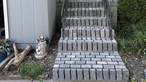 A house with a gray exterior, a white door, and a set of stone steps leading to the front door.