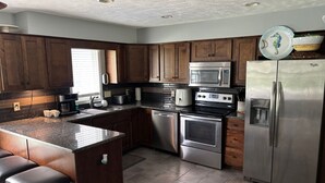 A modern kitchen with wooden cabinets, stainless steel appliances, and a granite countertop.