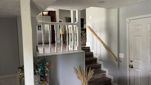 A staircase with a wooden handrail, a white door, and a white railing.