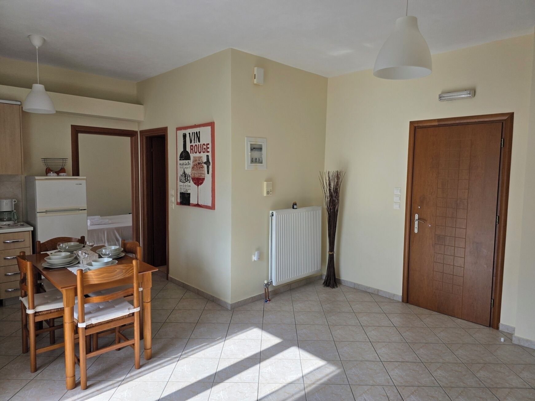 A spacious kitchen with a dining table set for four, a refrigerator, and a radiator.