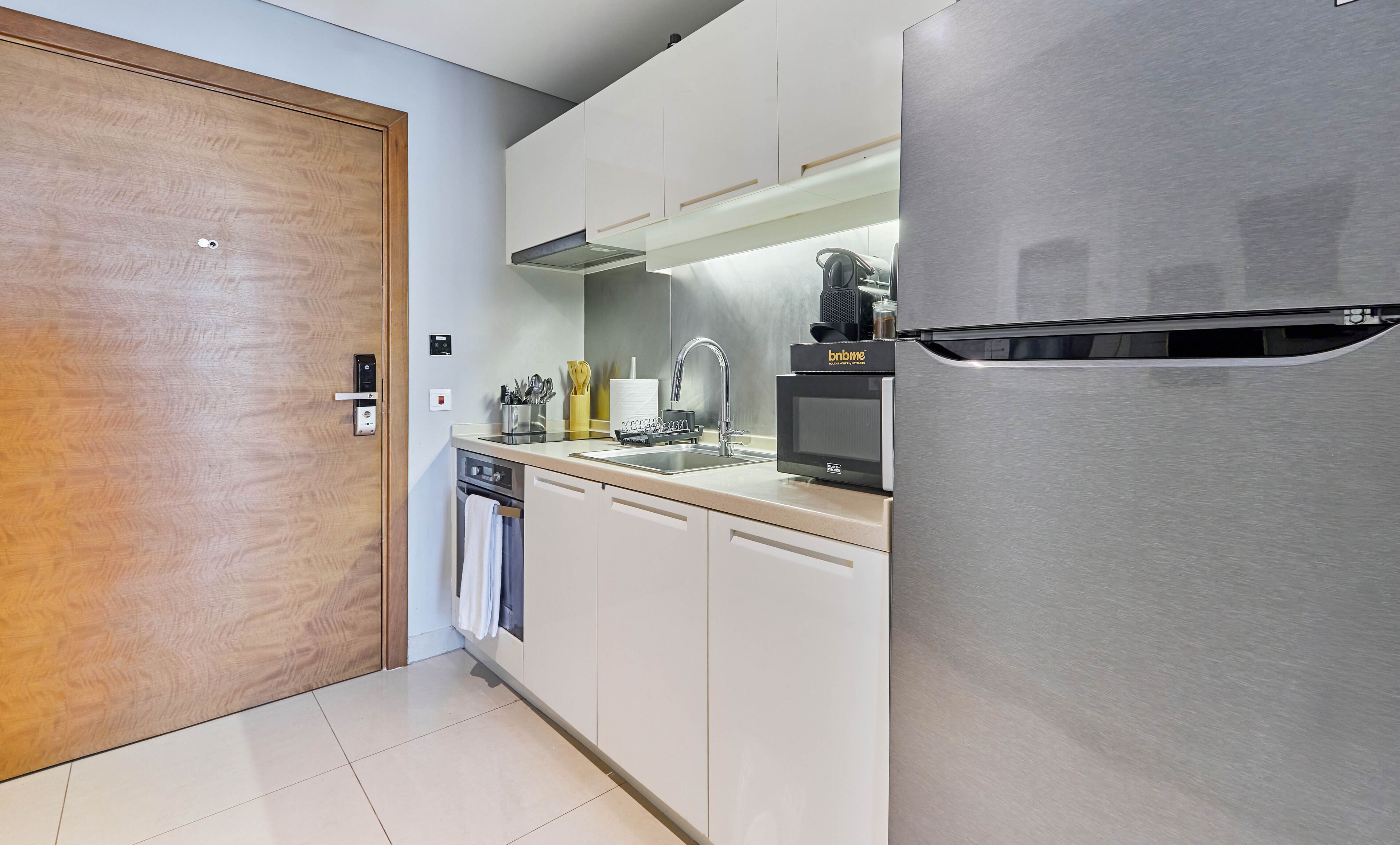 Una cocina moderna con un refrigerador de acero inoxidable, un horno empotrado y un lavamanos con grifo.