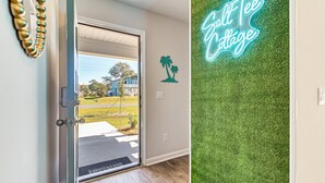 Een deur die uitkomt op een kamer met uitzicht op een blauw huis en een groen gazon.