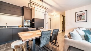 A modern kitchen with a dining area, a sofa, and a framed picture on the wall. - Rivulet - Comfortable apartment in Châtel (Châtel)