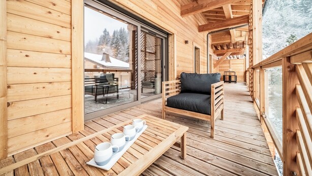 A wooden deck with a sofa and a table with cups and saucers. - Rivulet - Comfortable apartment in Châtel (Châtel)