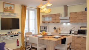 Une cuisine moderne dotée d’un îlot central, de meubles en bois et d’un téléviseur à écran plat fixé au-dessus de l’îlot.
