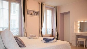 Une chambre à coucher avec un lit, un bureau doté d’un miroir et une guitare.