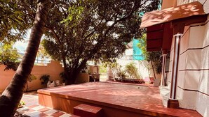 Un patio con piso a cuadros, una palmera y un edificio de techo rojo.