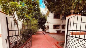 Una entrada con portón a una zona residencial, con un sendero de tejas rojas que lleva a un edificio con múltiples ventanas.