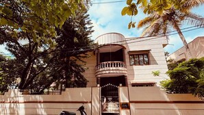 Un edificio de dos pisos con balcón, entrada protegida por una reja y una moto estacionada.