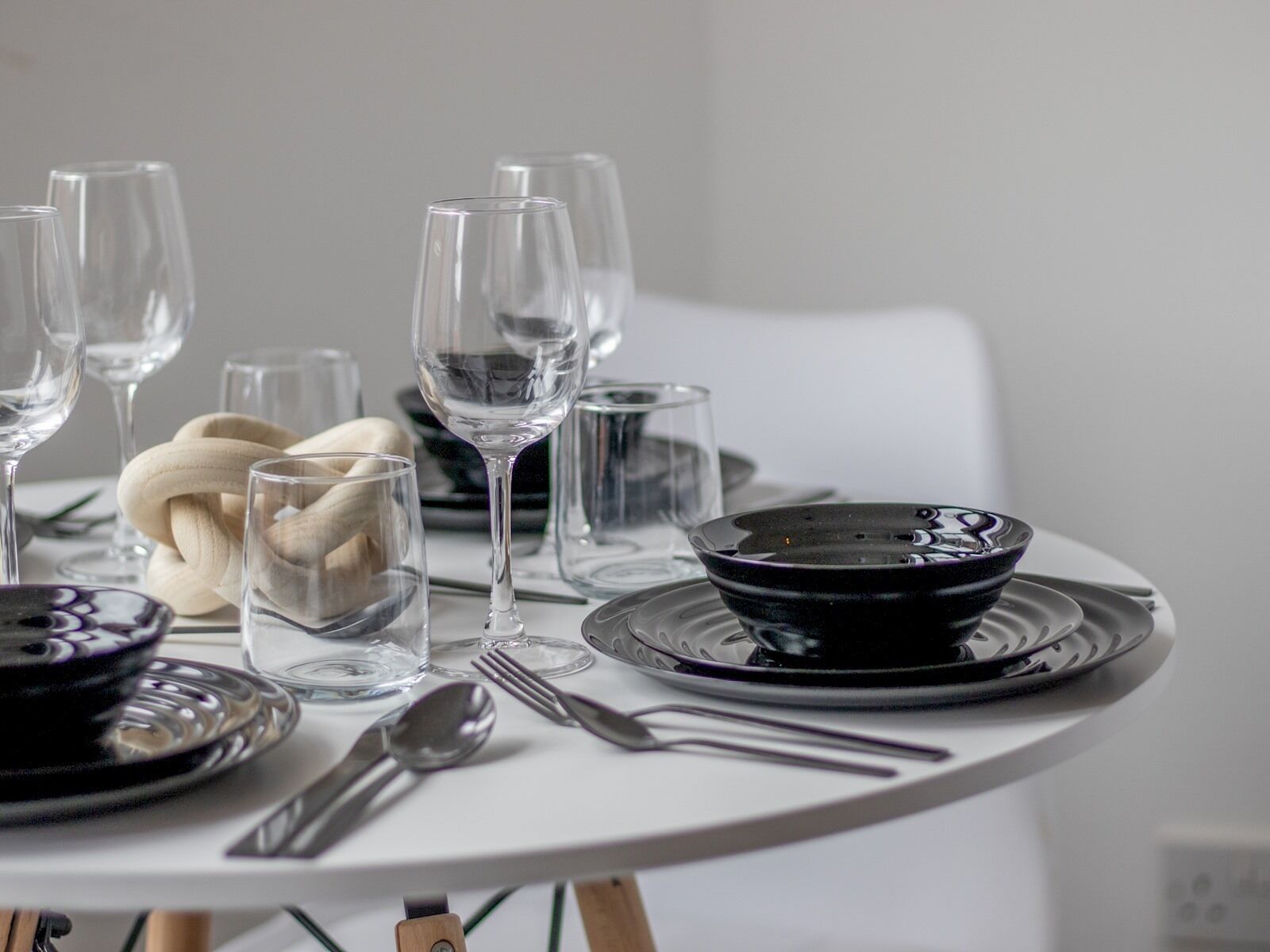 A dining table set with clear glassware, a black bowl, and silverware.