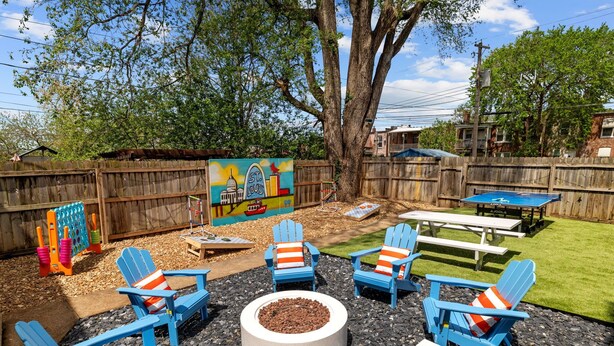 A backyard with a fire pit, blue Adirondack chairs, a picnic table, and a mural. - Family Getaway with Backyard + Games: Near Downtown St. Louis (St. Louis)