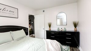 Ein Schlafzimmer mit einem Bett, einem Schminktisch, einem Spiegel und einem Willkommensschild.