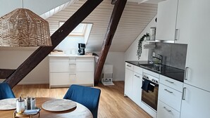 Une cuisine moderne avec des armoires blanches, un plan de travail noir et un four encastré.