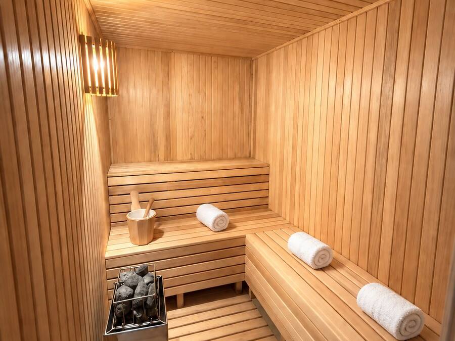 A sauna with wooden benches, a bench heater, and a bucket with a wooden scoop.