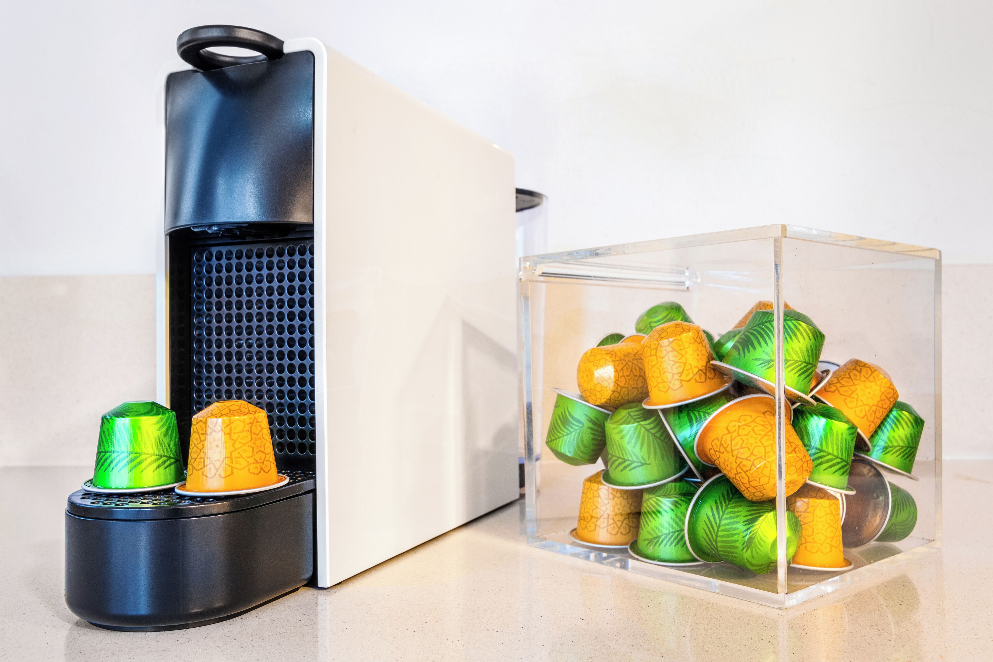 A black and white appliance with a transparent container filled with green and yellow patterned cups.