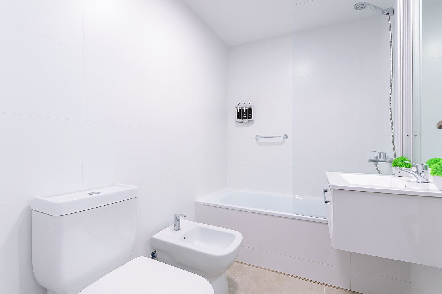 A modern bathroom with a toilet, bidet, bathtub, and a sink with a mirror.