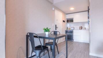 A compact kitchen with modern appliances, a dining area with a table and chairs, and a potted plant.