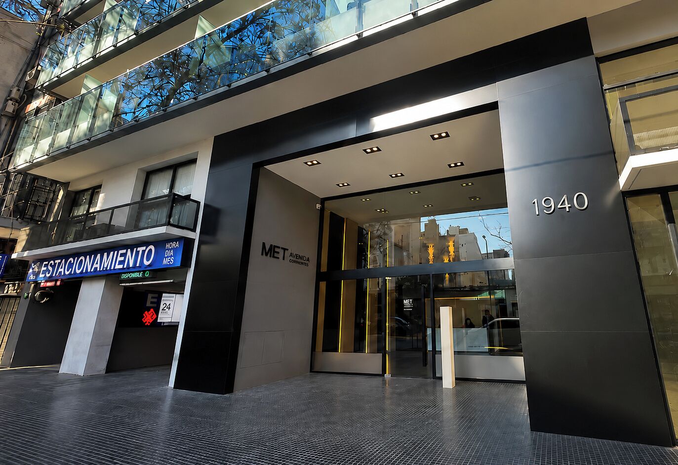 A modern building entrance with a glass facade, a sign for 'MET AVENIDA CORRIENTES,' and the year '1940' displayed.