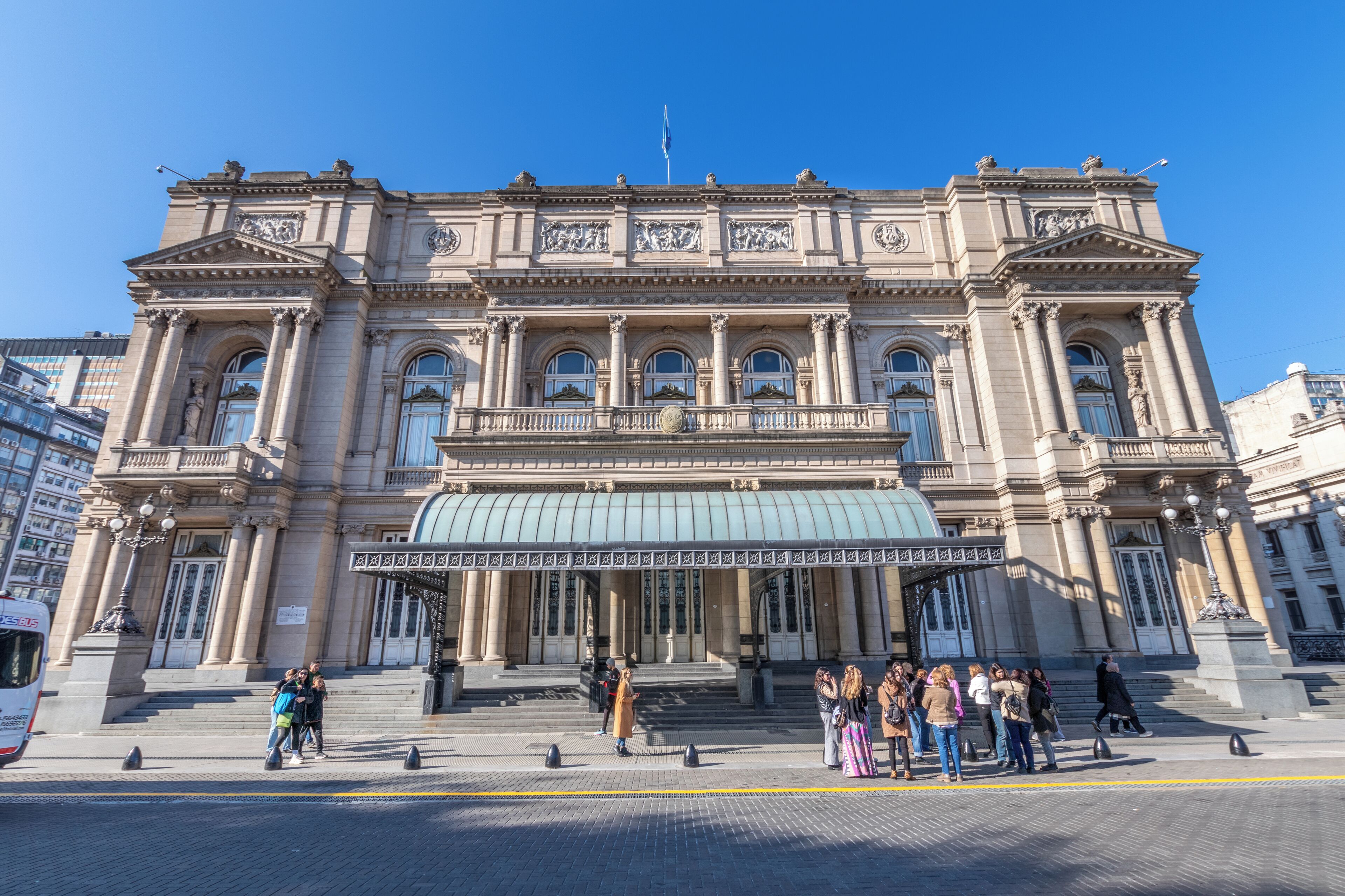 A large, historic building with classical architecture, featuring a prominent entrance with steps and columns, and a large dome.