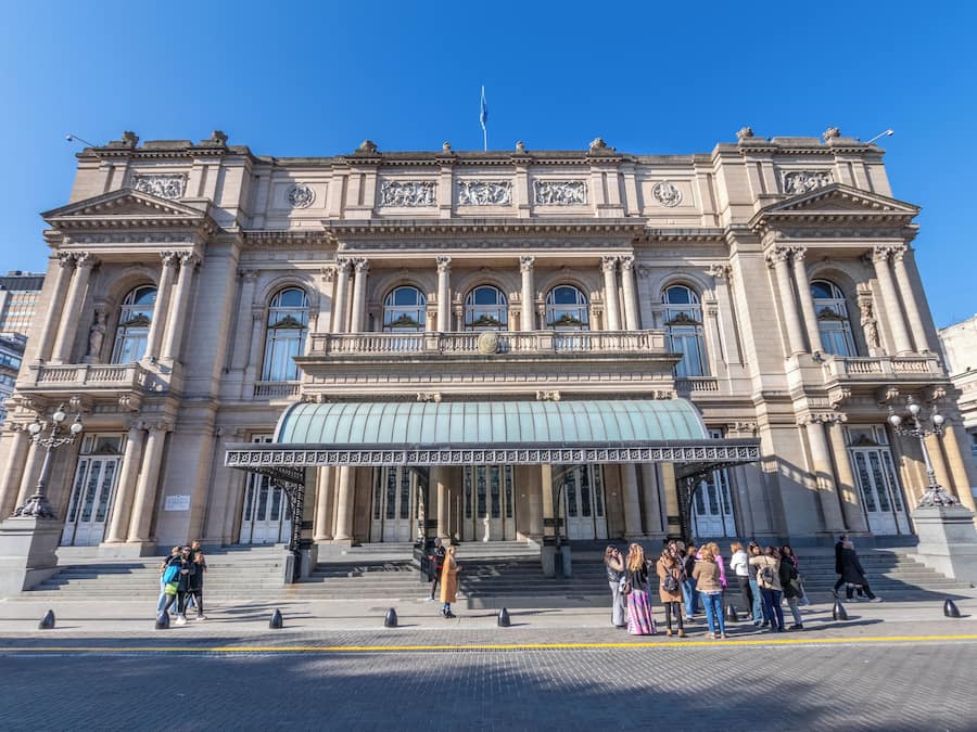 A large, historic building with classical architecture, featuring a prominent entrance with steps and columns, and a large dome.