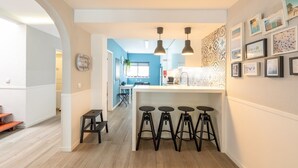 Une cuisine moderne dotée d’un îlot central, de tabourets de bar, de luminaires suspendus et d’un pare-feu décoratif.