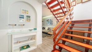 Un intérieur moderne avec un escalier en bois, des murs blancs et un meuble vitrine en verre.