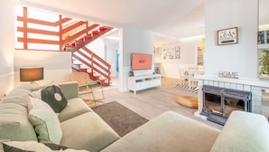 Un salon moderne avec un escalier, une cheminée et un téléviseur.