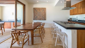 Een moderne keuken met een houten eettafel, barstoelen en een groot schiereiland met een ingebouwde kookplaat.